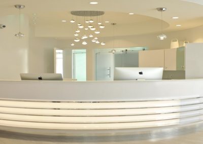Modern front desk with silver accents and tiered lighting