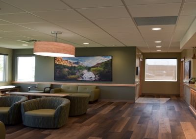 Large waiting room with green couches and wooden accents