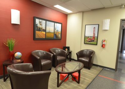 Commercial office waiting room with red feature wall and leather couches