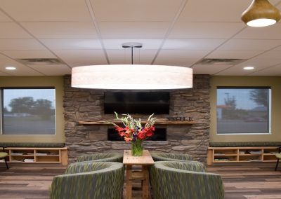 Large round feature light hanging up green couches in dental office waiting room