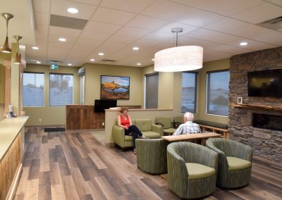 Dental waiting room designed with natural elements with wooden floor and stone fireplace