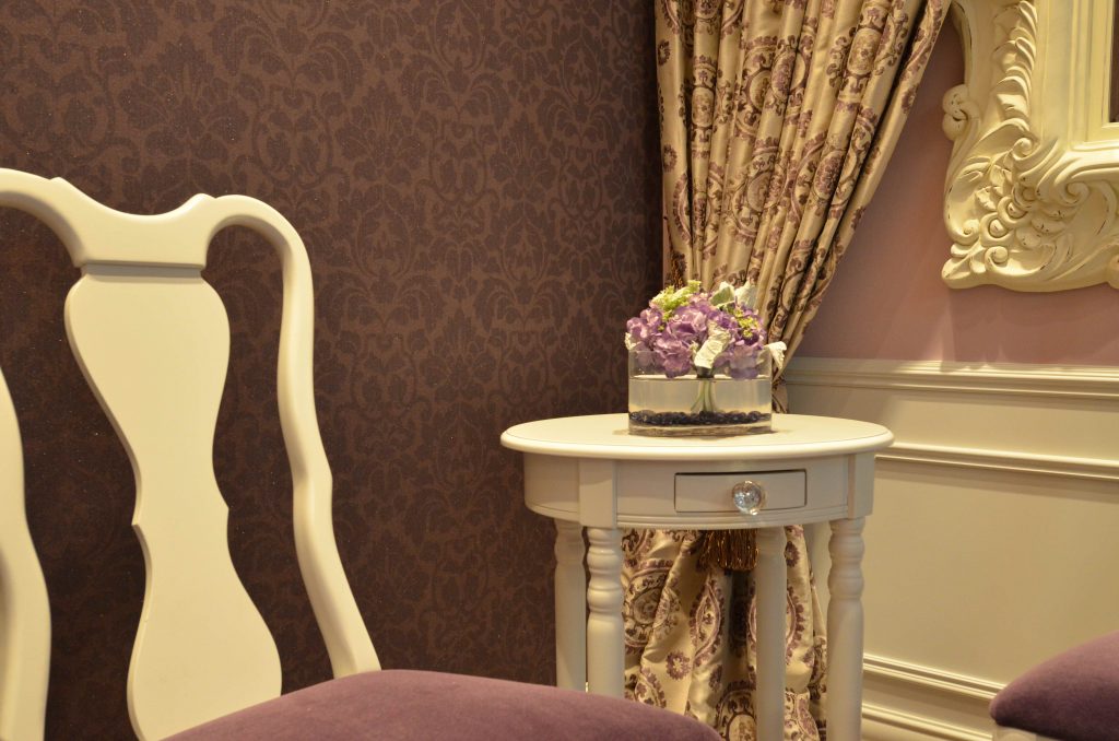Violet damask wallpaper with matching violet velvet chairs and white side table