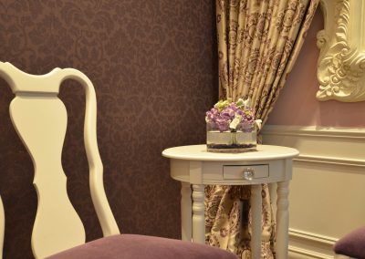 Violet damask wallpaper with matching violet velvet chairs and white side table