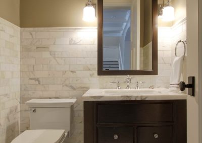 Renovated powder room with white counter top and dark cabinets