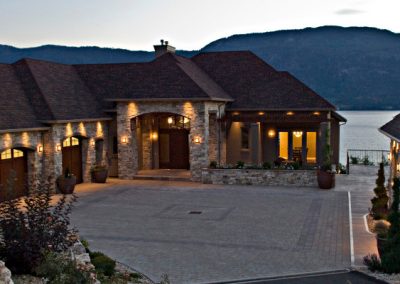 Custom home design with rock trim exterior and view of the lake