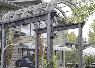 Arched pergola in backyard surrounded by trees