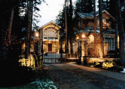 Driveway leading up to gated house surrounded by forest