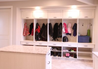 Large white mudroom with island in the middle for storage