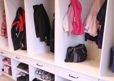 White mudroom with hanging areas and white drawers and shoe holders