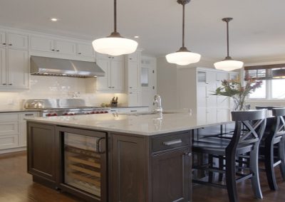 Custom kitchen island design with bar chairs and built in wine fridge