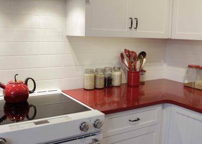 Red kitchen countertops accompanied by custom white cabinets